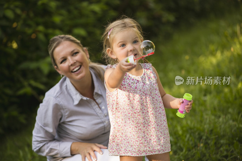 母亲和女儿在花园里吹肥皂泡