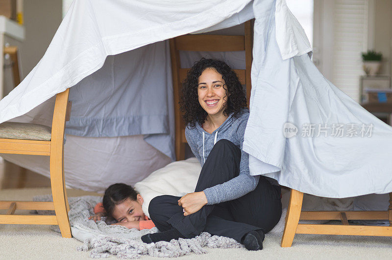 年轻的民族妈妈和女儿躺在客厅地板上谈论生活
