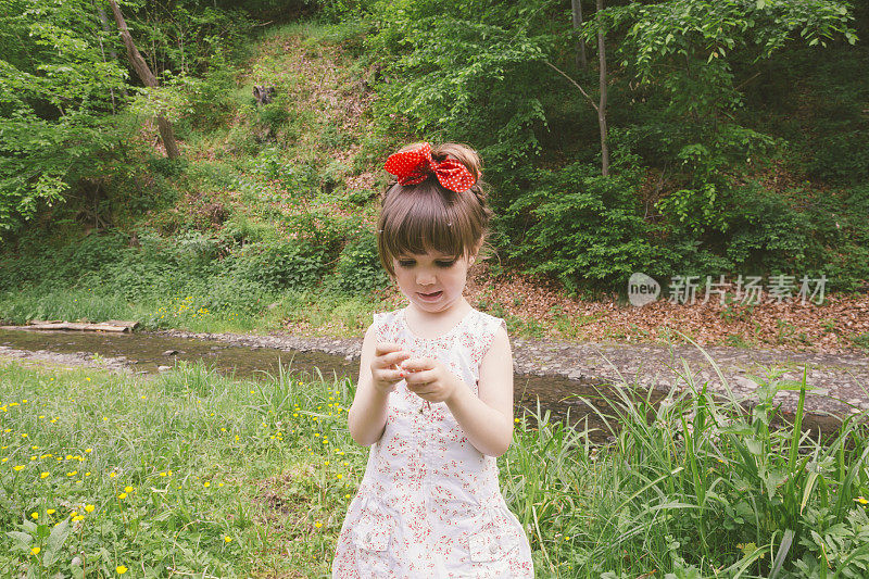 美丽可爱的小女孩红发蝴蝶结站在户外的自然环境中