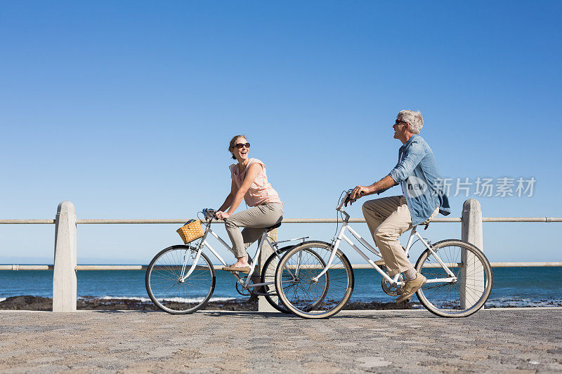 快乐随意的情侣在码头上骑自行车