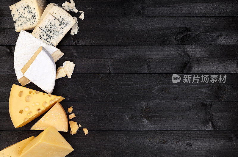 黑色的木桌上放着不同种类的奶酪。俯视图