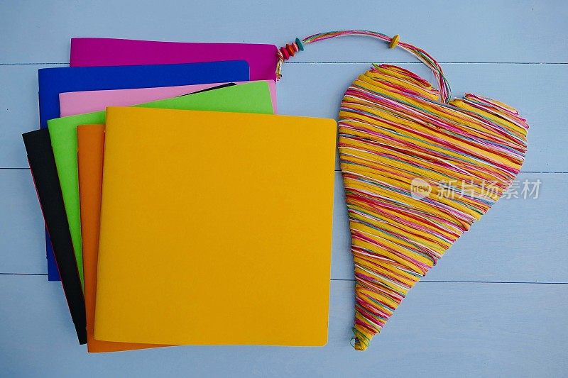 彩色的笔记本和一个彩色的心躺在右边