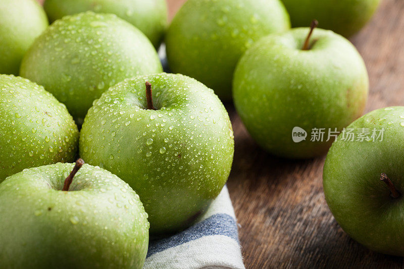 一个木碗里装着成熟的青苹果，放在一张旧的质朴的桌子上。木制背景上有用的水果。俯视图
