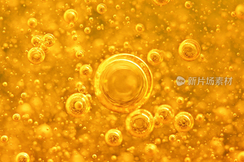 金色的背景与大的和小的金色气泡油里面的黄金液体。