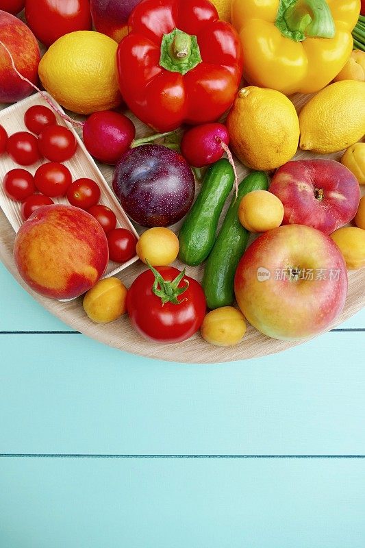 石灰绿色的桌子上放着一个装有水果和蔬菜的圆形木盘子