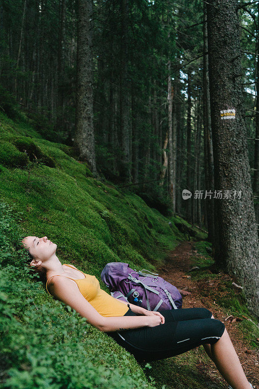 在长满青苔的山林中徒步旅行后休息的女人