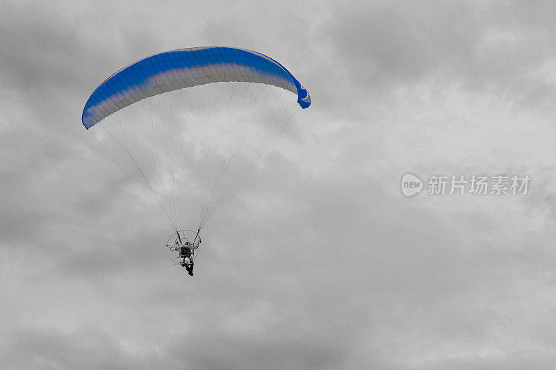 Para-motor在黑白相间的天空上飞行。在画布上是一个彩色图像。