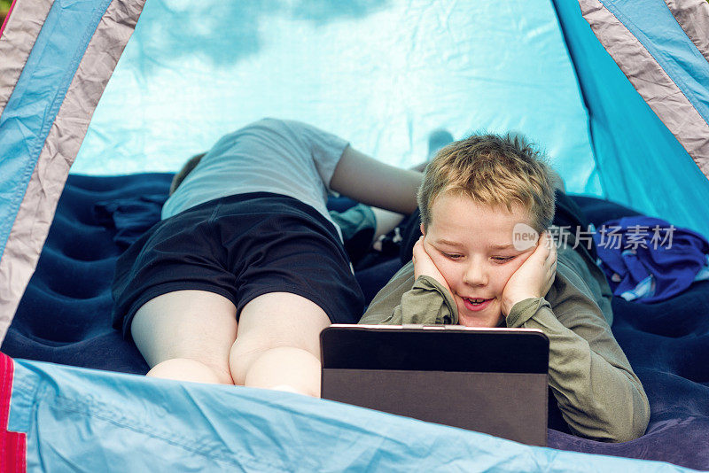孩子在帐篷里用平板电脑观看流媒体视频