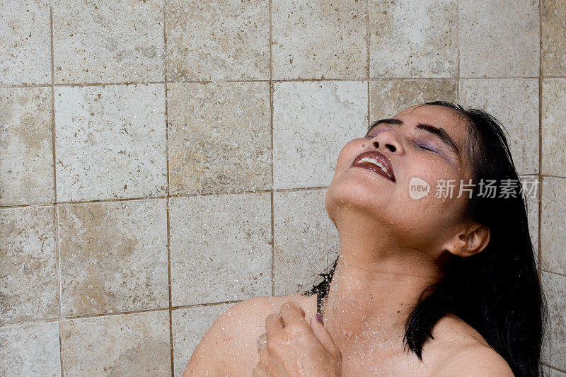 美丽的亚洲女人在淋浴与水在脸上