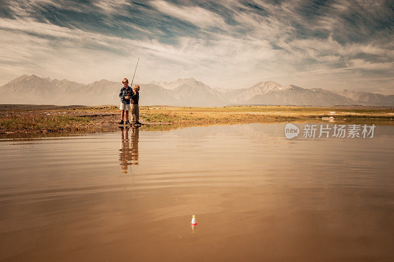 两个小男孩在山上的湖上钓鱼