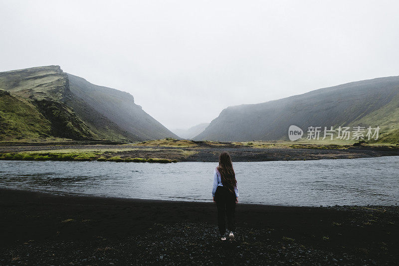 女人呆在冰岛高地美丽的湖和山附近