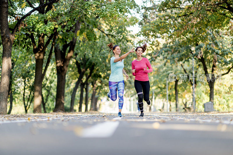 两个女性朋友在阳光公园的小路上慢跑