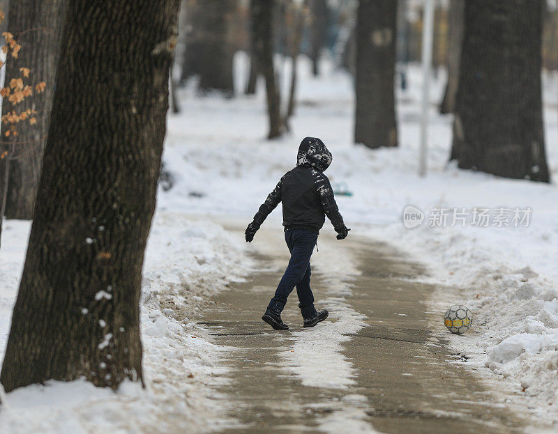 男孩在冬天在公园里踢球