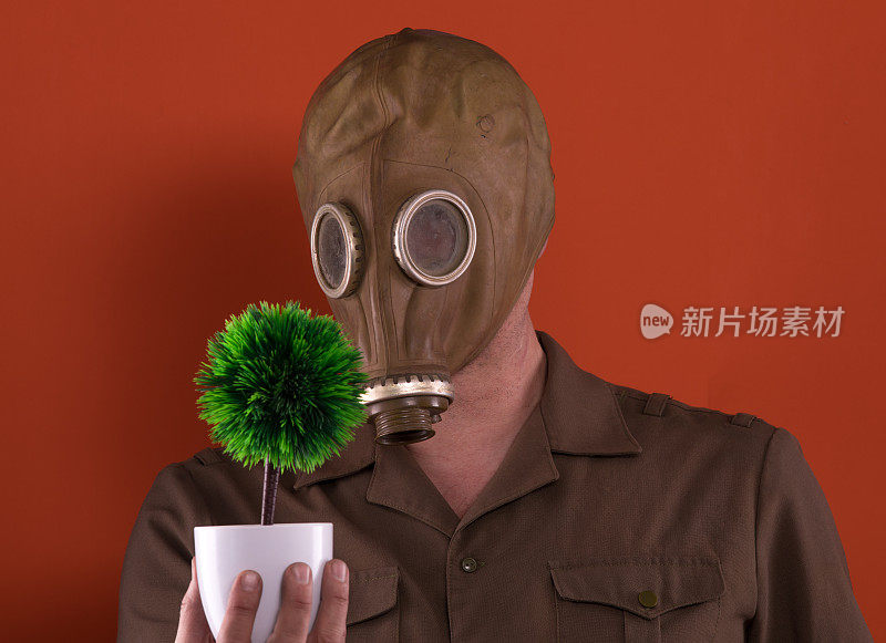 一个戴着防毒面具，手里拿着植物的人