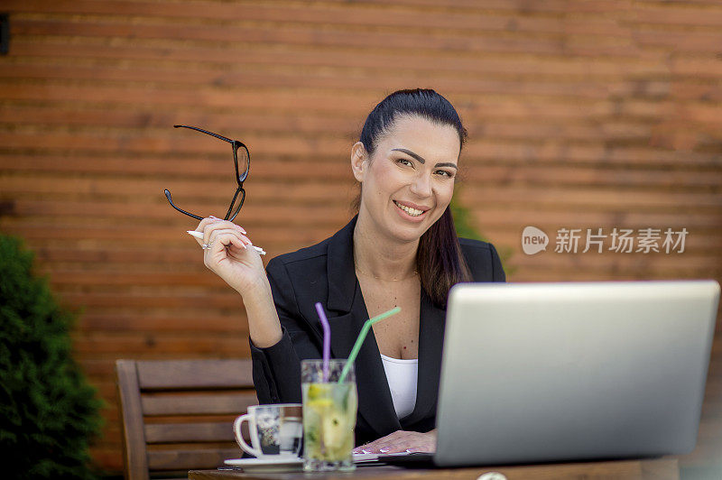 年轻的女商人在café用笔记本电脑工作