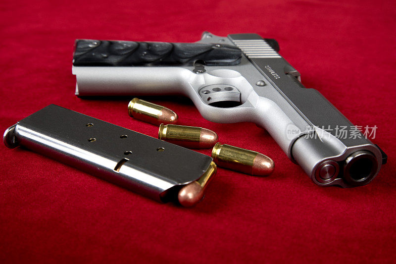 45口径半自动手枪，装有子弹和弹夹，红色背景