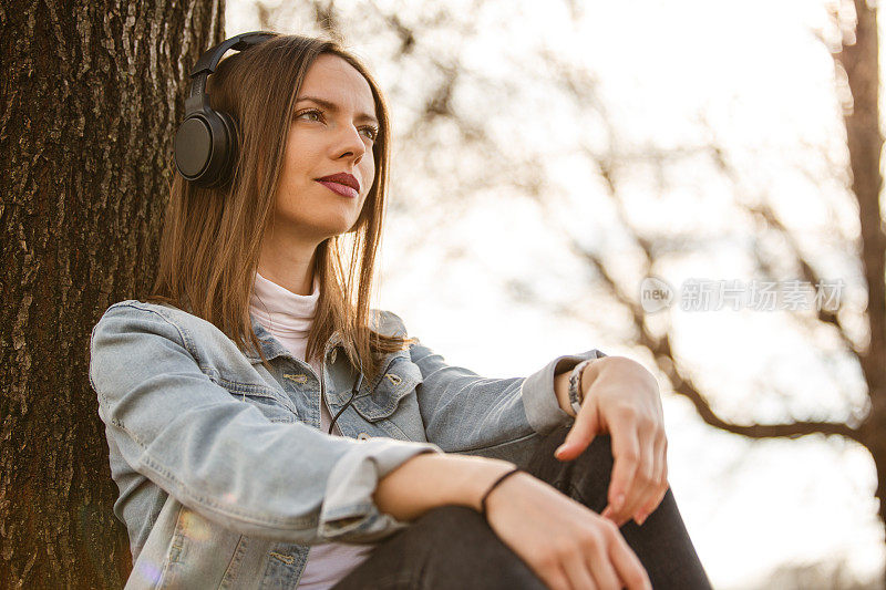 年轻女子戴着耳机在户外听音乐