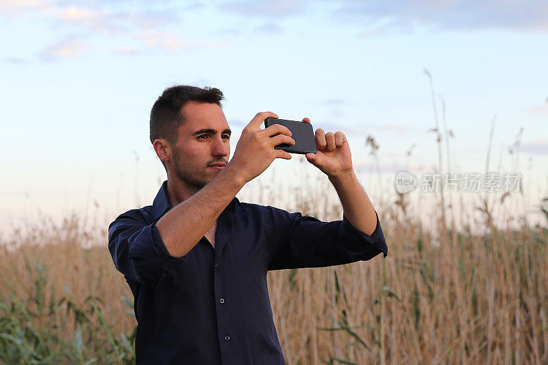 男人在户外用手机，近距离，用手机在大自然中拍照。用我手中的智能手机捕捉这一刻。