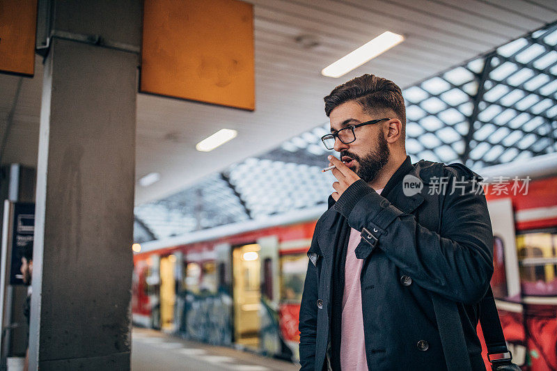 年轻人站在火车站抽烟