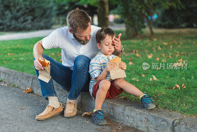 爸爸和儿子在公园里吃汉堡