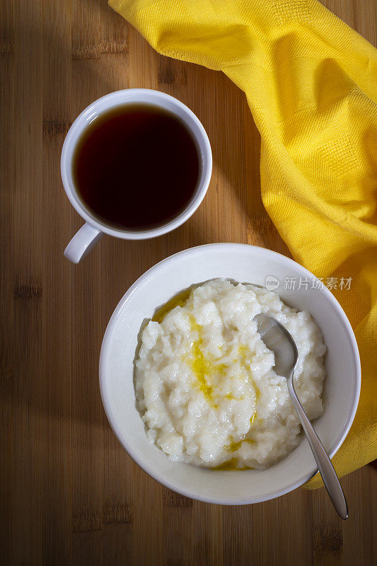 米粥碗和一杯红茶在木桌和黄色餐巾-俄罗斯传统食品库存照片库存照片