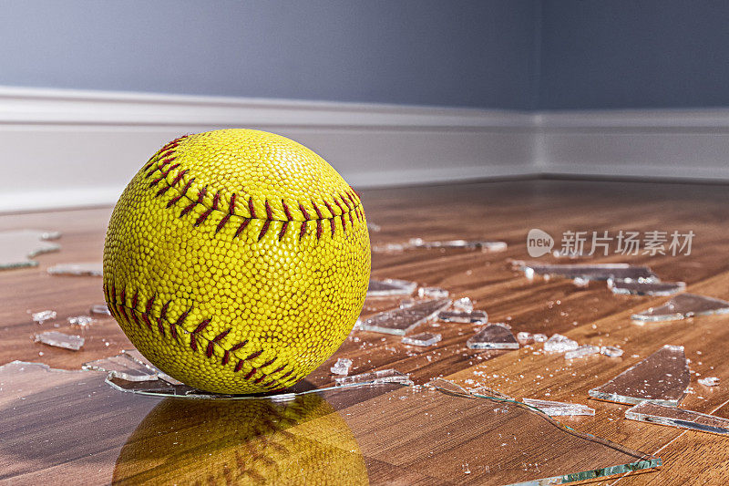 地板上有一个黄色的垒球和碎玻璃