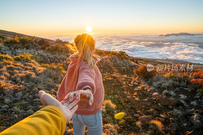 跟我来概念;一个年轻的女人在太阳的云层上带着男朋友去火山