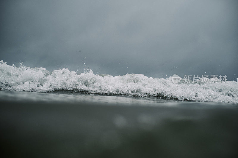 在康沃尔纽基菲斯特拉海滩阴暗的一天，透过海面看到一个接近的破浪。