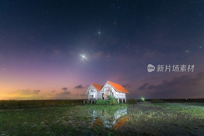 山上有银河和粉红的光。晚上多彩的景观。夏天的星空和山峦。美丽的宇宙。太空背景与星系。旅游的背景