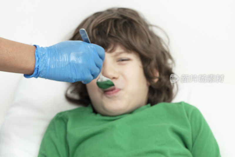 生病的小男孩从医生那里吃药水