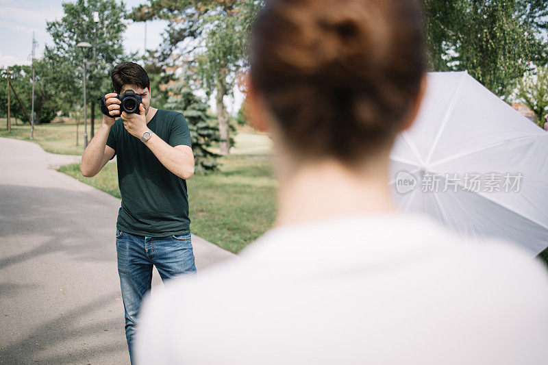 年轻的摄影师在公园里给一个女人拍照