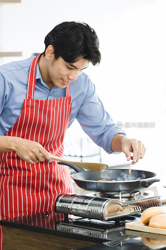 一个亚洲人在炉子上的平底锅里煎汉堡包。