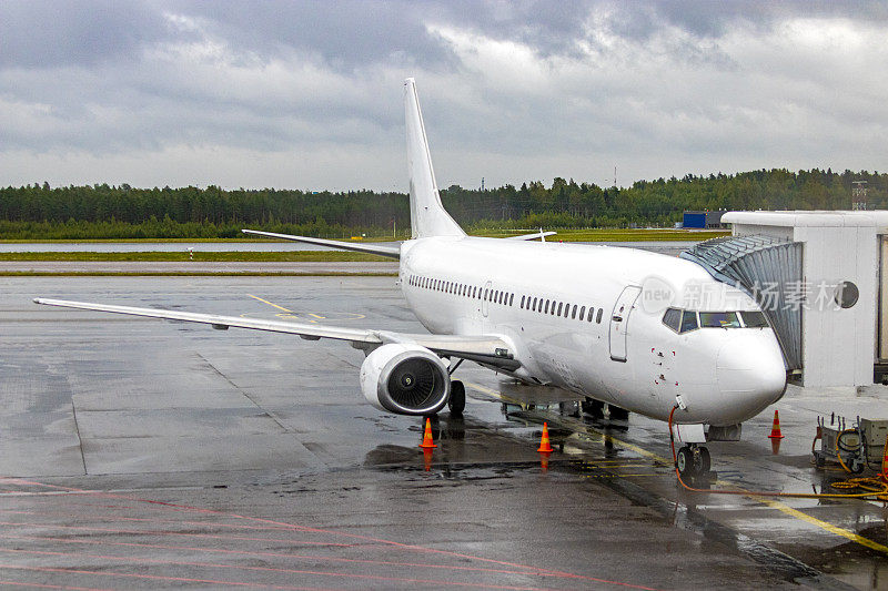 白色波音737-33R停在斯堪的纳维亚机场航站楼装载乘客