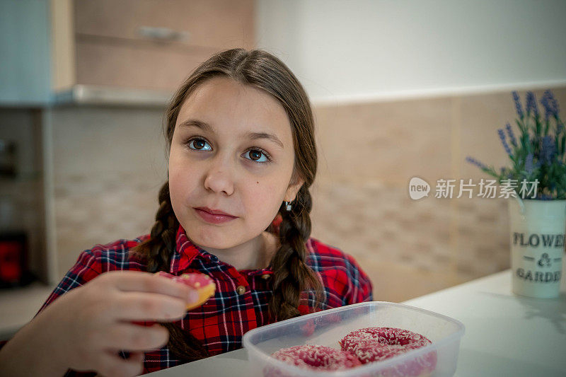 对孩子的饮食。悲伤和不快乐的孩子触及甜甜圈。孩子们的美味食物。孩子在看甜甜圈。垃圾食品上瘾。