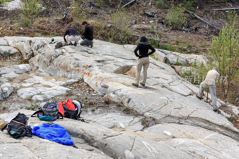 一组工人和地质学家站在地质露头现场工作。
