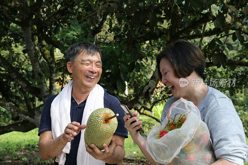 一对夫妇站在公园里拿着水果