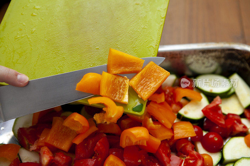 用刀将切碎的辣椒从砧板上滑下，放入不锈钢锅中