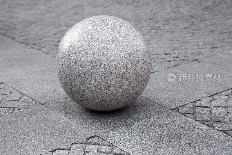 灰色花岗岩球在人行步道上以石砖铺装广场，城市景观城市街道建筑元素，无人。