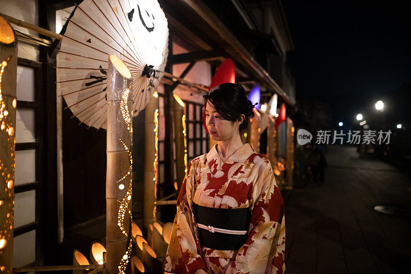 在浴田的日本妇女在晚上为传统的日本竹节行走