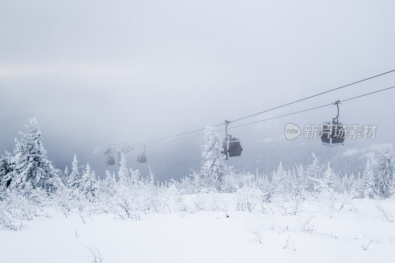 缆车在滑雪胜地的雪覆盖的斜坡上，冬天的树木，山上的景观