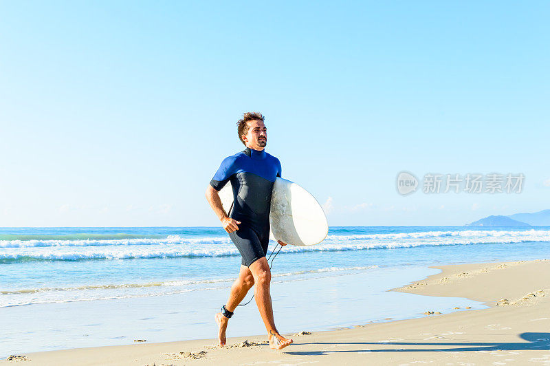 一位正在接受训练的专业冲浪手，带着冲浪板从海上出海