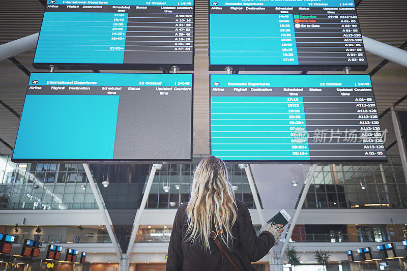 一个女人在机场检查她的航班时间的照片