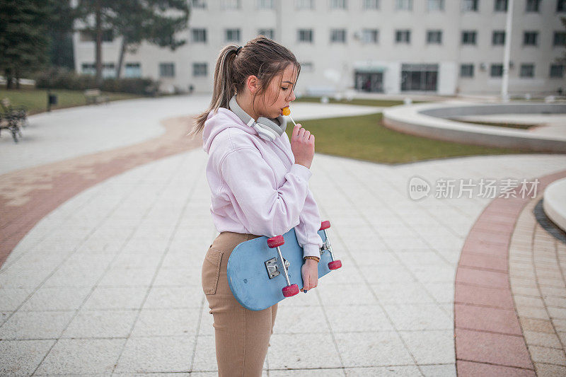 年轻女子用滑板舔棒棒糖