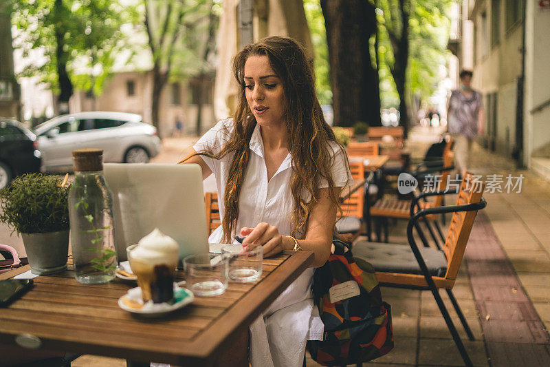 女商人一边用笔记本电脑一边在咖啡桌上喝着咖啡享受工作