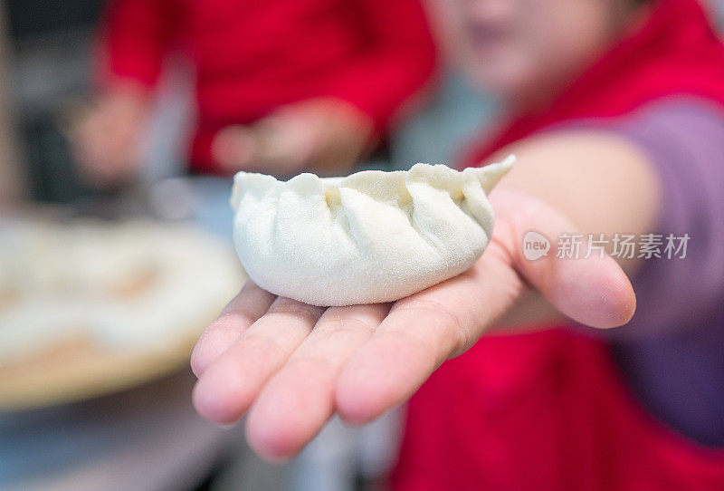 一个年轻女子拿着饺子，展示她的手工作品