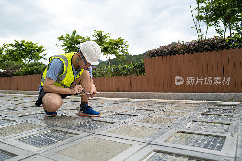 工程师在地面上的太阳能电池板旁边工作