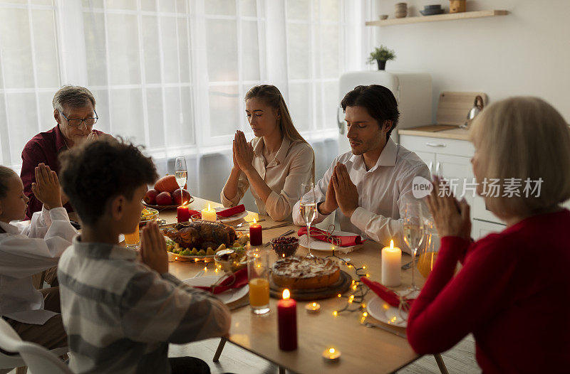 在圣诞节晚餐前，全家一起祈祷，在室内的餐桌上感谢上帝