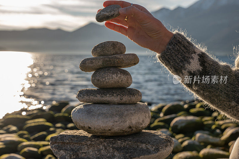 近距离观察女人在湖边堆砌岩石的手