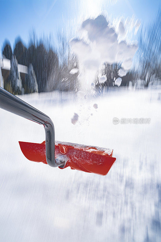 一个低视角的雪铲投掷在半空中的雪与镜头光晕从太阳。