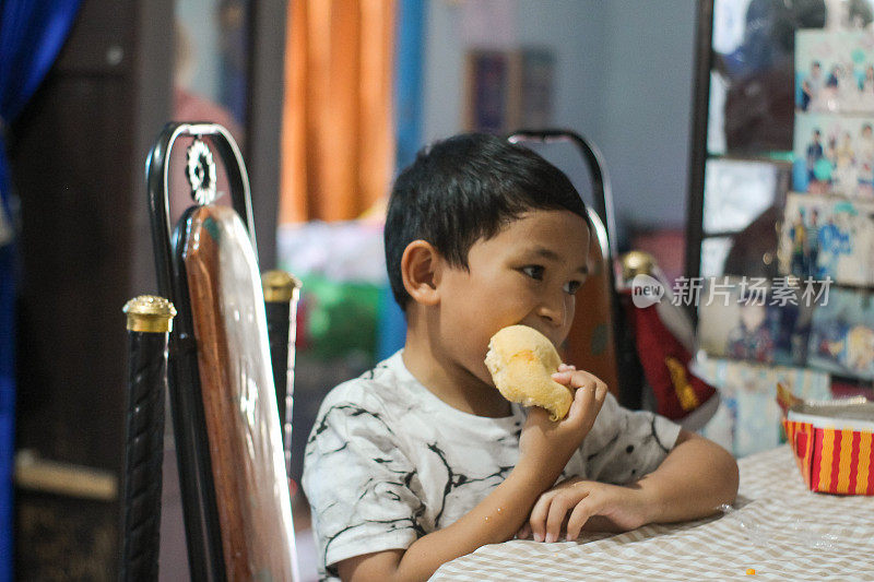 男孩坐在家里吃面包